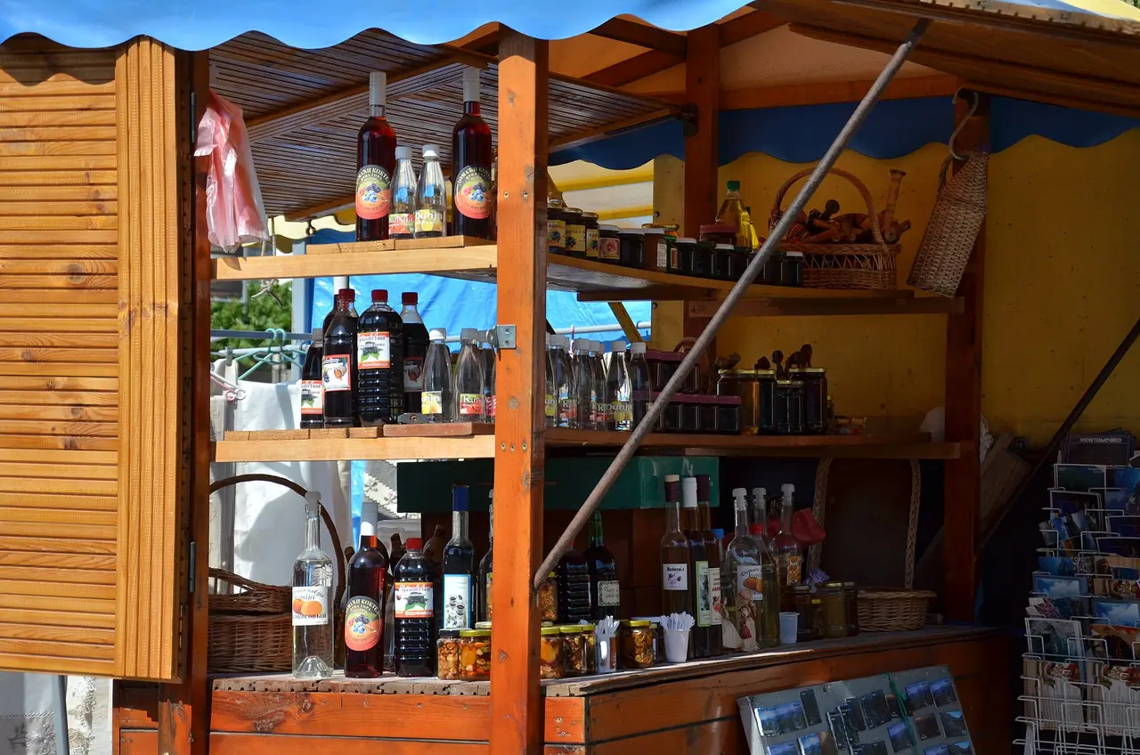 A wooden roadside stall in Montenegro selling bottles of rakija, wild pomegranate syrup, honey and preserves
