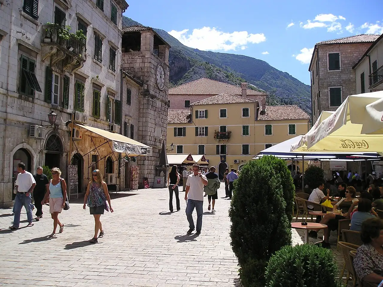 The main square of Kotor old town with the clock tower, cafes and the mountains rising behind