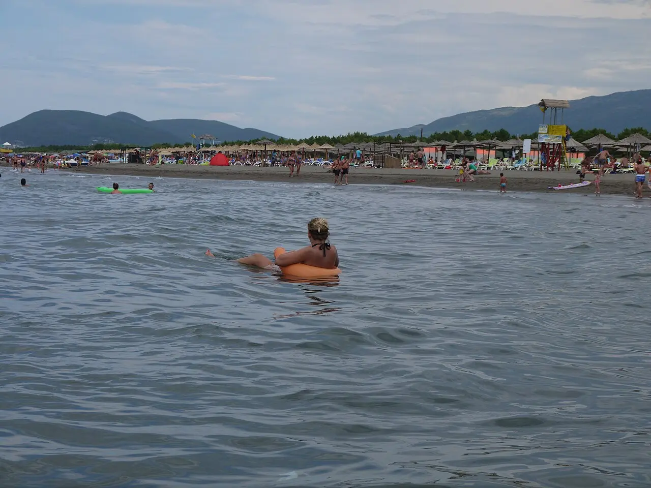 Velika Plaža at Ulcinj - a long stretch of sand with swimmers and sun-loungers, hills behind