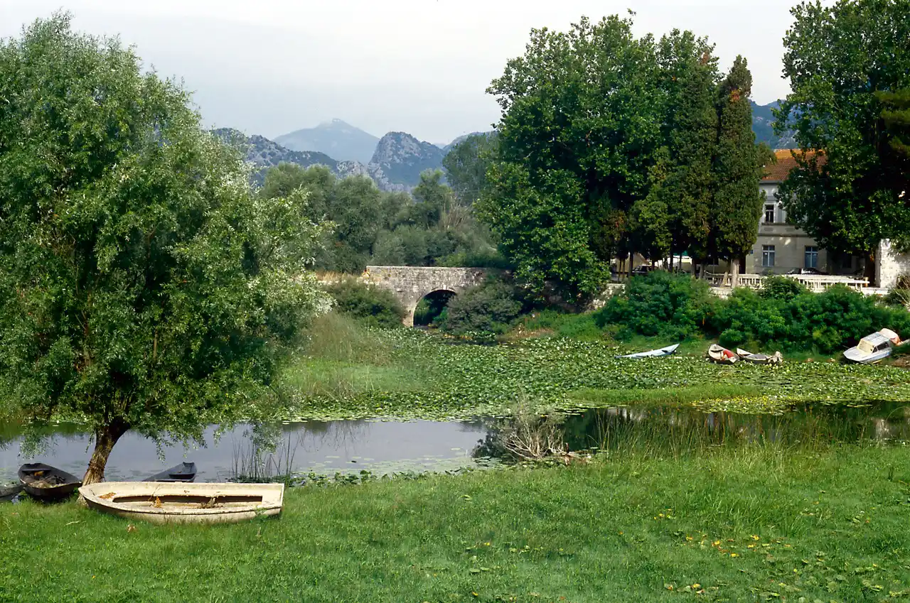 The village of Virpazar on Lake Skadar with its stone bridge, moored boats and the surrounding hills