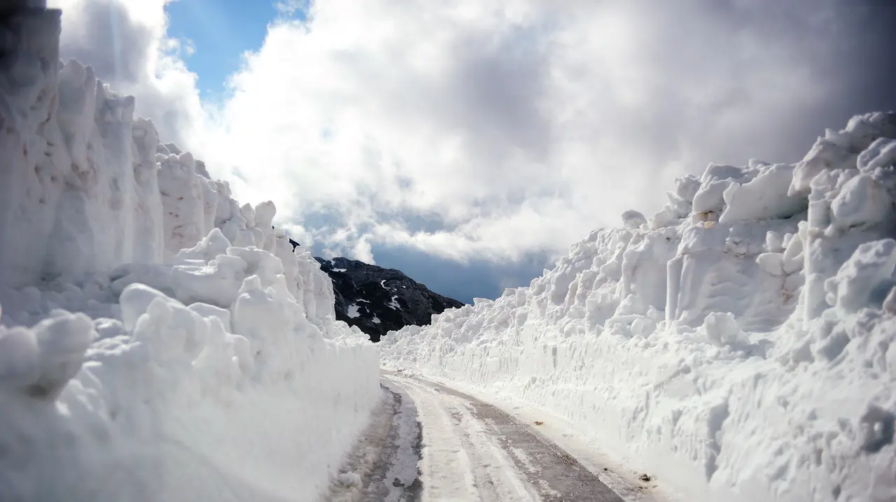 A cleared mountain road cutting between walls of deep snow on the Durmitor plateau in Montenegro