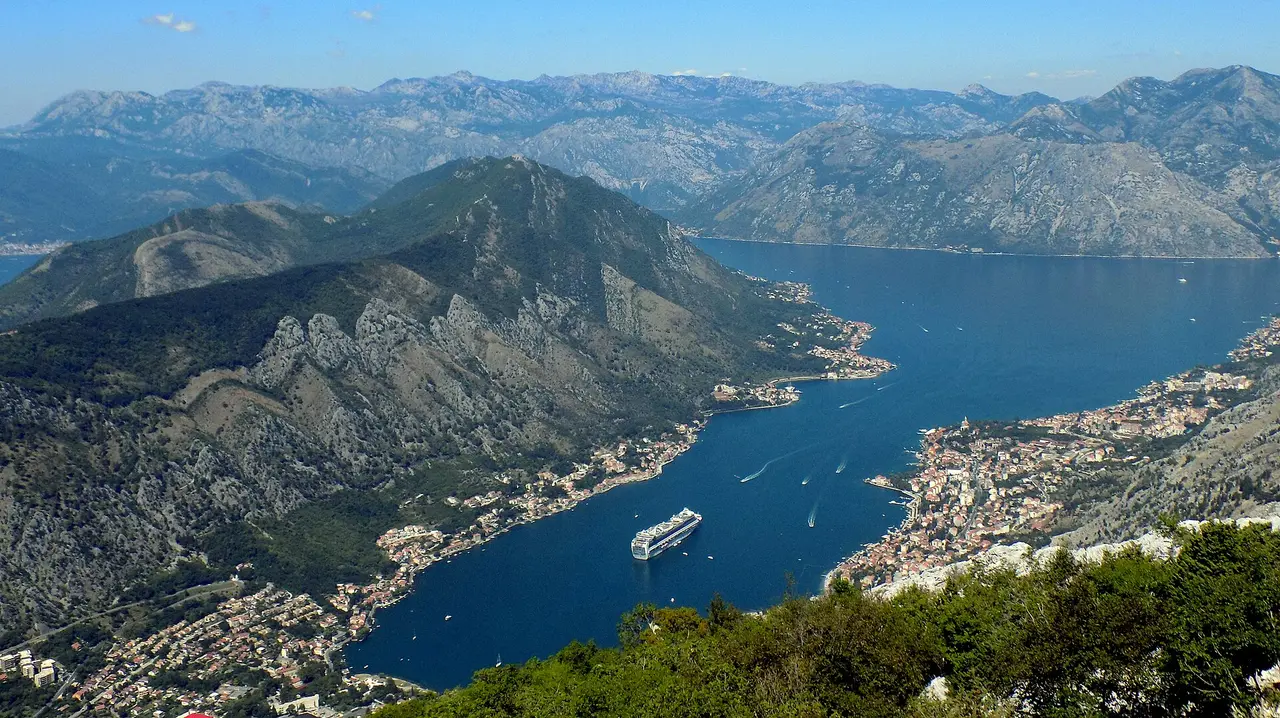 The Bay of Kotor and old town seen from high on the mountain road above, a cruise ship in the bay