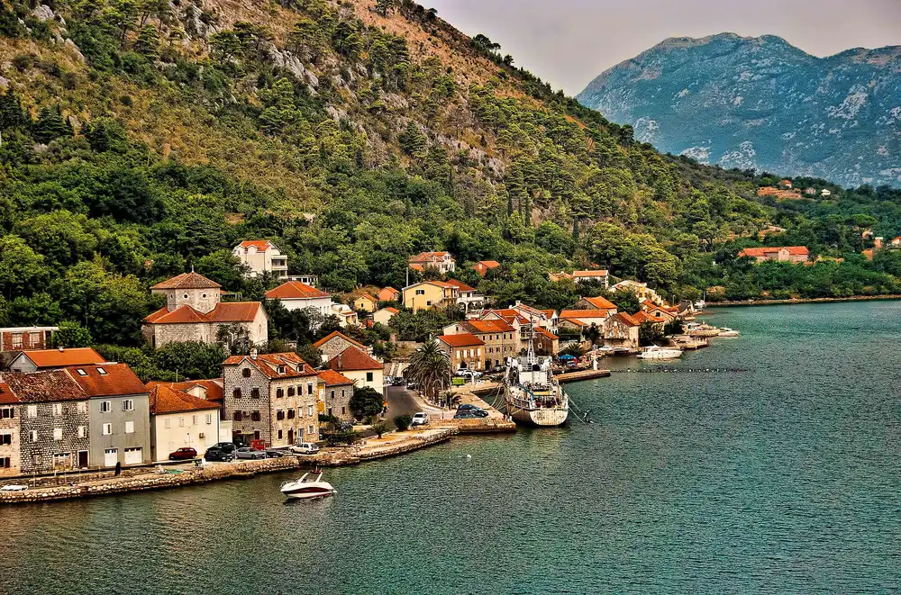 Stone waterfront houses and deep green water along the Dobrota shore of the Bay of Kotor, Montenegro