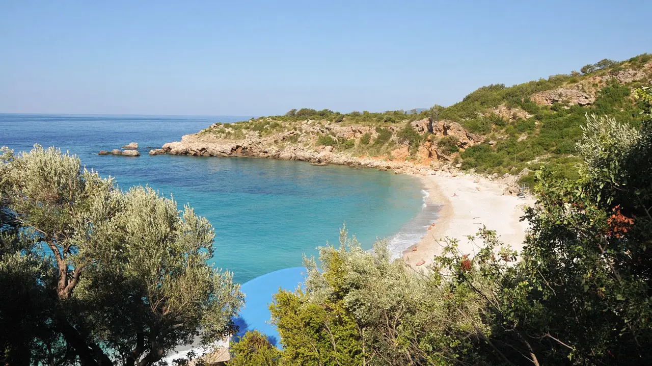 Clear turquoise water in the sheltered cove of Drobni Pijesak beach on the Montenegrin coast