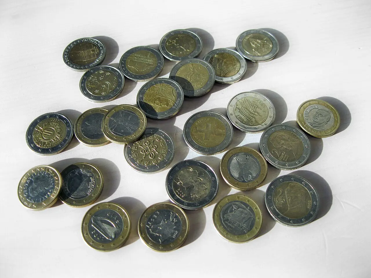 A scattered pile of assorted one and two euro coins from different eurozone countries