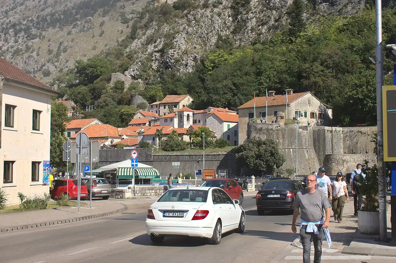 Cars and pedestrians on the road at the edge of Kotor's old town walls, Montenegro