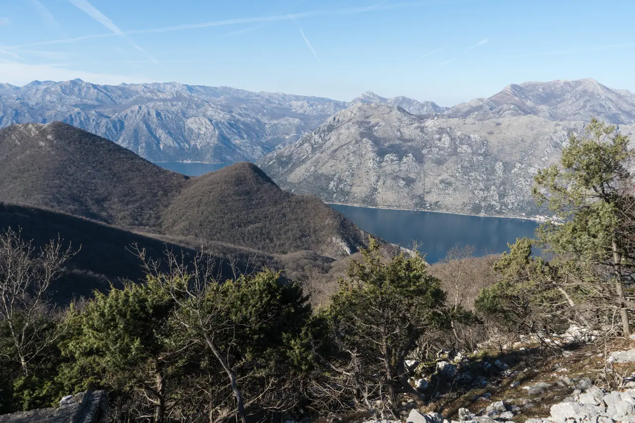 The Bay of Kotor seen from Vrmac mountain, a narrow blue inlet winding between steep grey mountains
