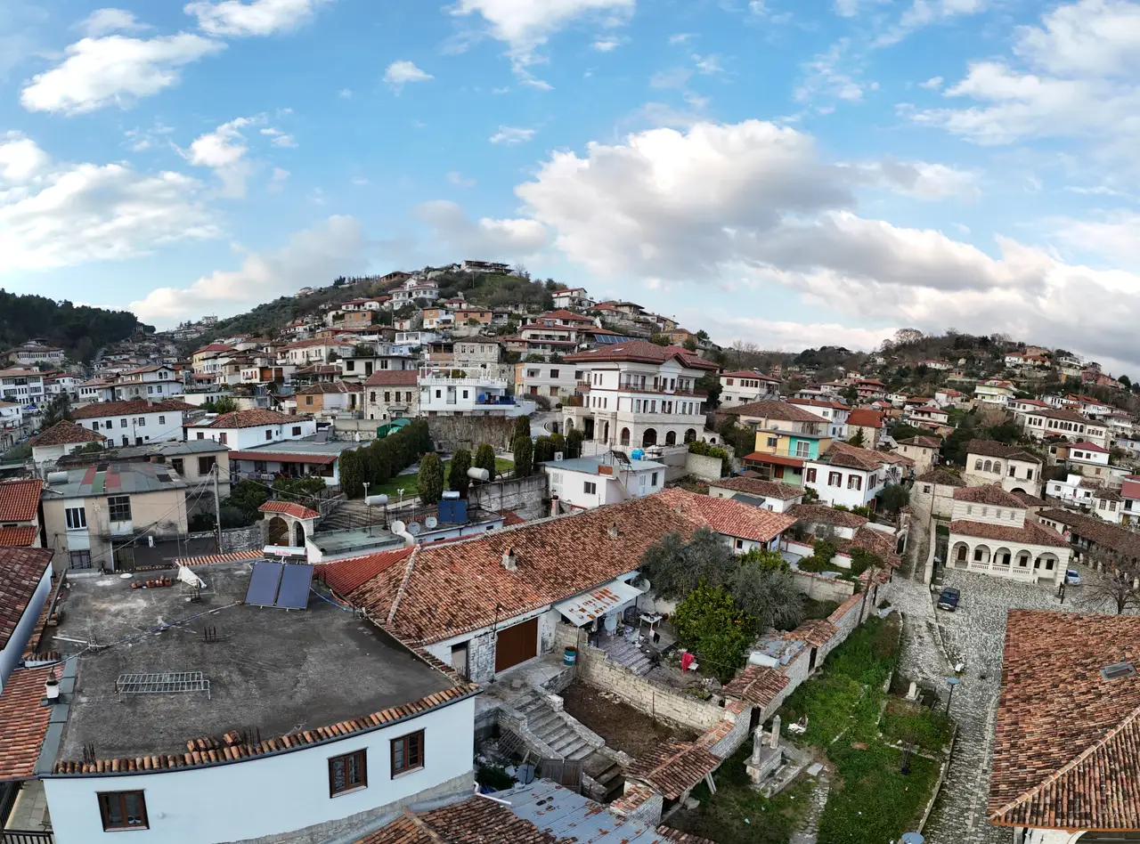 The Ottoman hillside town of Berat in Albania, rows of white houses with many windows and red-tiled roofs climbing a green slope