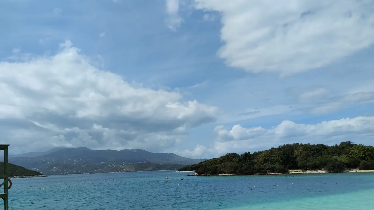 Turquoise water and a green wooded islet off the white-sand beach at Ksamil on the Albanian Riviera