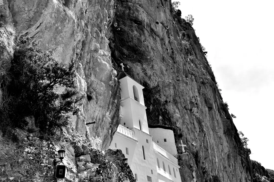The whitewashed Ostrog Monastery set into a vertical grey cliff in the Montenegrin mountains