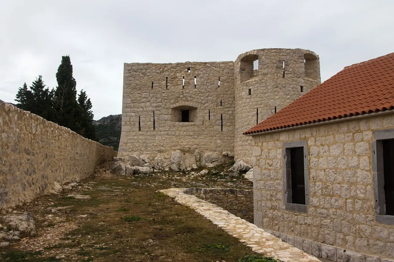The restored stone walls and round tower of Besac fortress above Virpazar on Lake Skadar