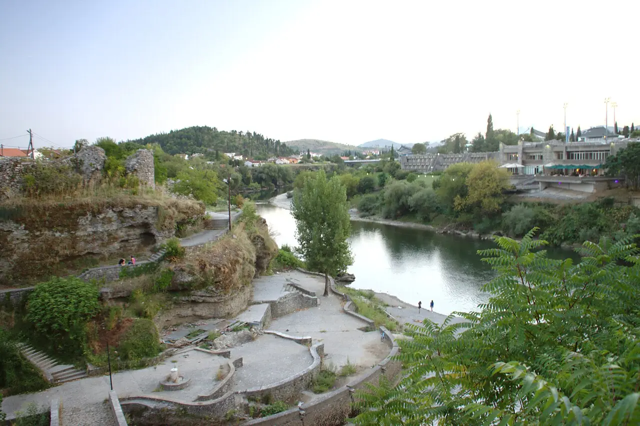 The Morača riverbank in Podgorica with trees, a path and the city beyond