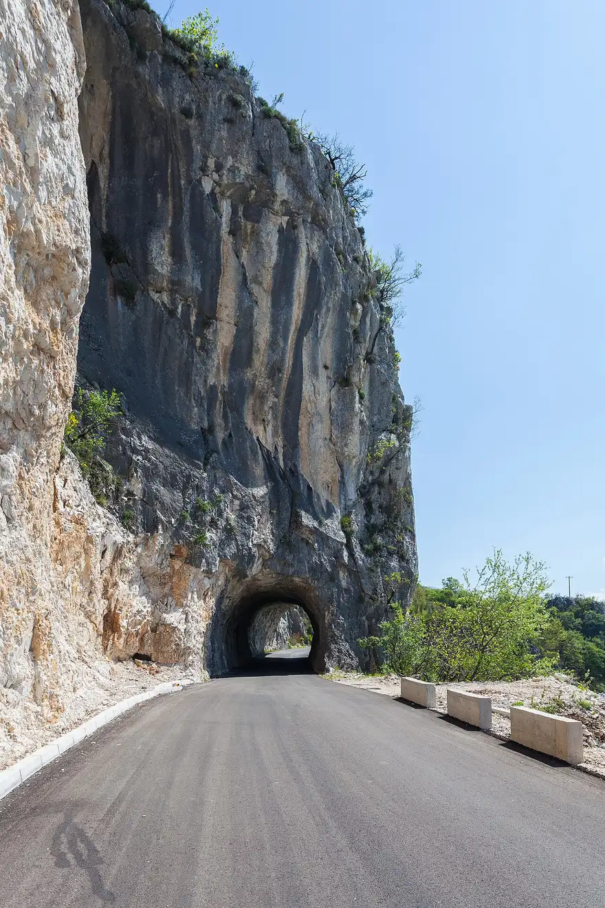 A tight hairpin on the cliff road up to Ostrog Monastery, rock wall on one side and a drop on the other