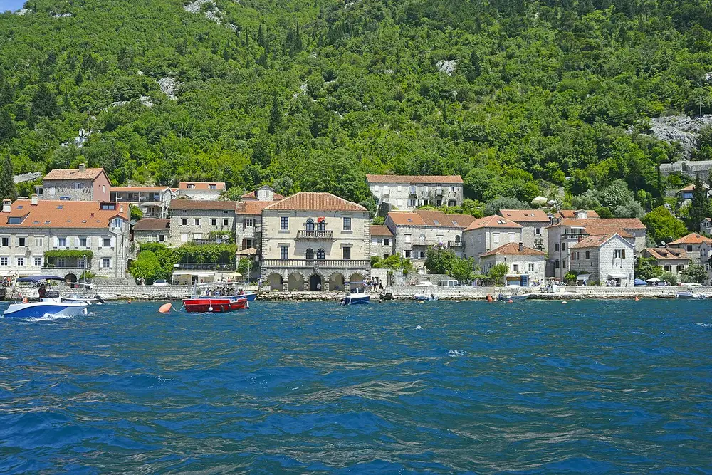 The stone palazzi of Perast lined along the shore of the Bay of Kotor, seen from the water