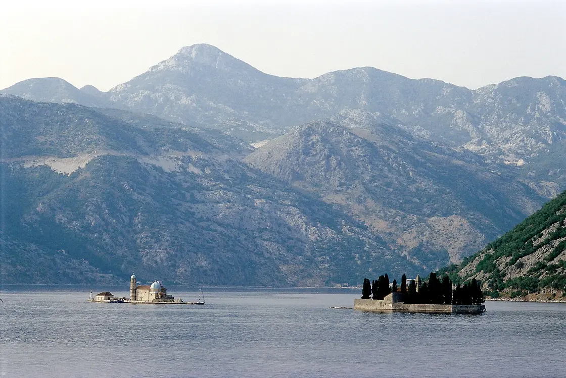 The two islets of Our Lady of the Rocks and St George side by side in the Bay of Kotor with mountains behind