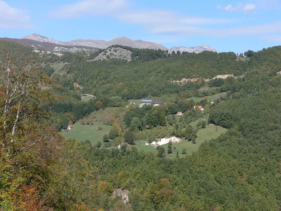 The stone church of Piva Monastery with wooded hills behind, near Plužine
