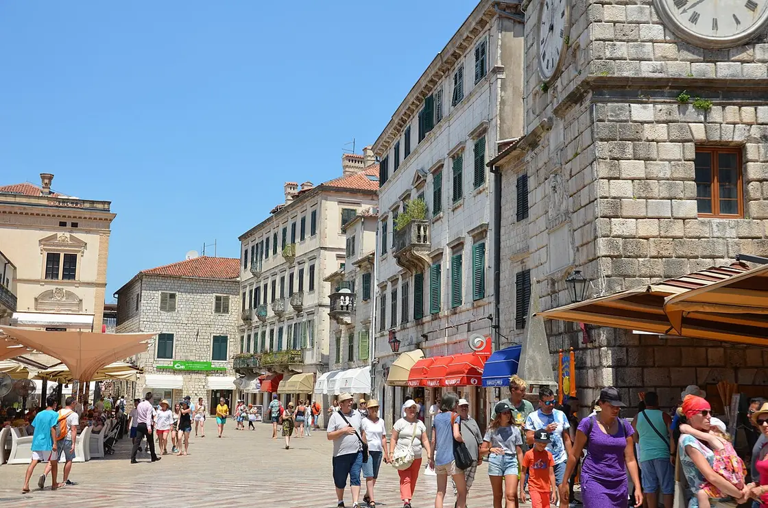 The clock tower and main square of Kotor's Old Town, crowded with visitors, the end of the journey from Podgorica