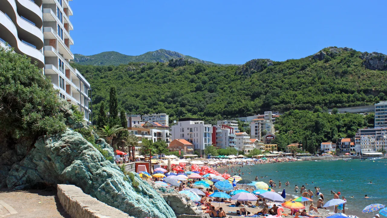 Pebble beach at Rafailovici lined with parasols in high season