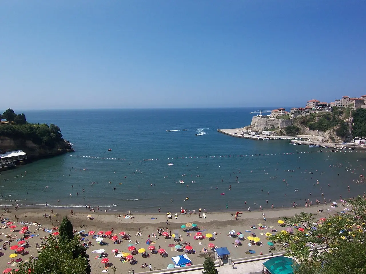 Mala Plaža, the sandy town beach of Ulcinj packed with umbrellas below the Old Town fortress on its rocky point
