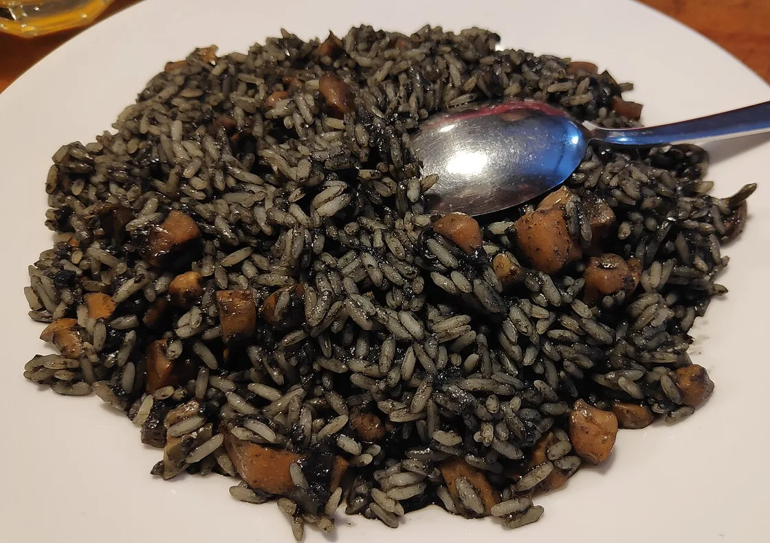 A plate of crni rižot, jet-black cuttlefish-ink risotto with pieces of squid
