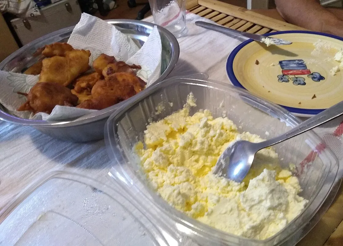 A bowl of fried priganice fritters next to a dish of soft white kajmak cream