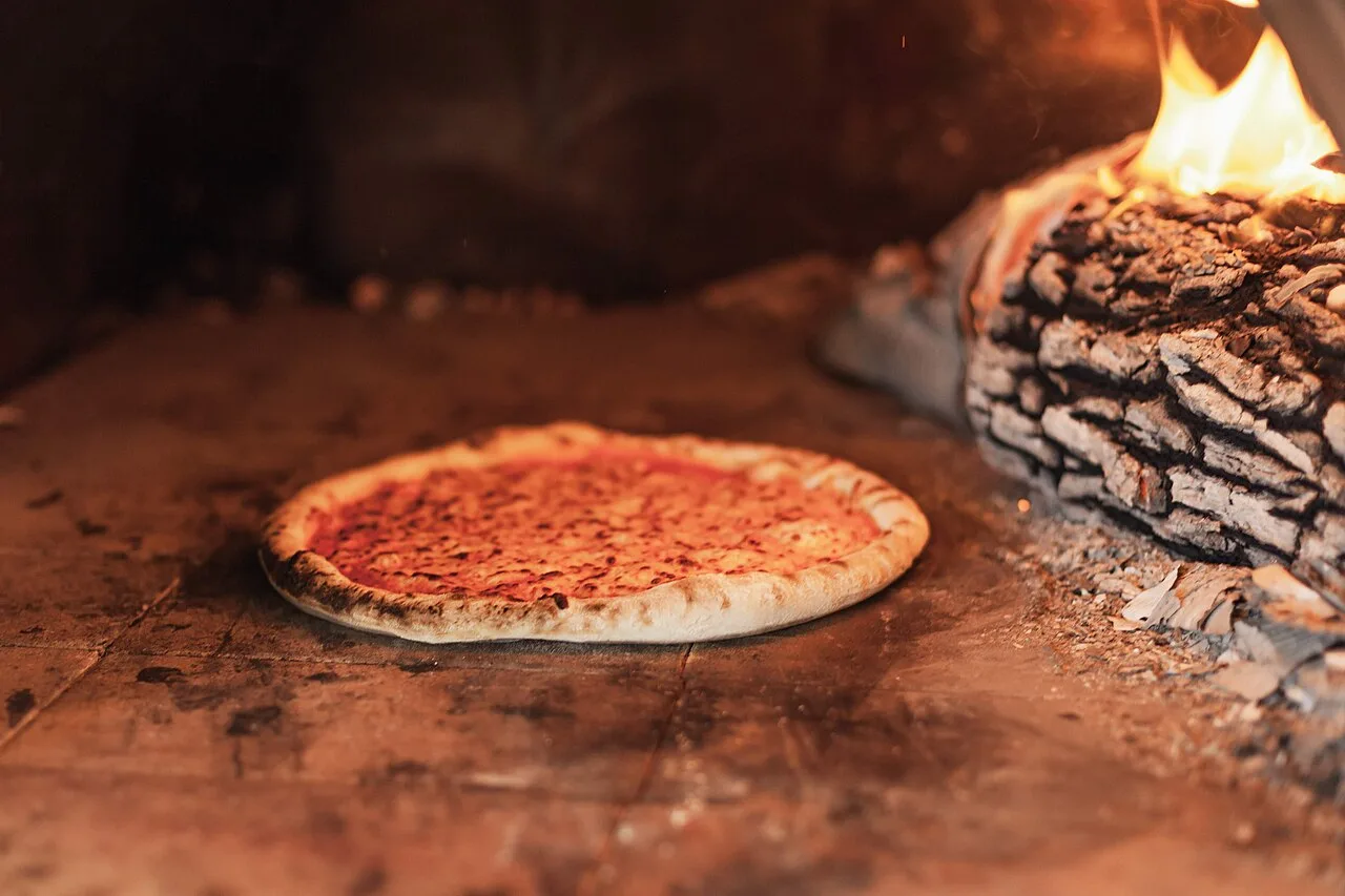 Wood-oven pizza with cheese and toppings fresh from the oven