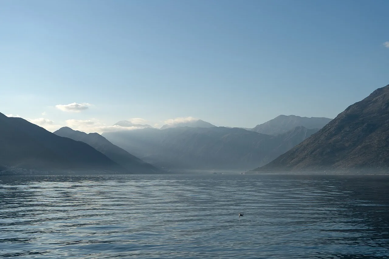 The Bay of Kotor seen from Dobrota, with waterfront houses, still water and steep mountains behind