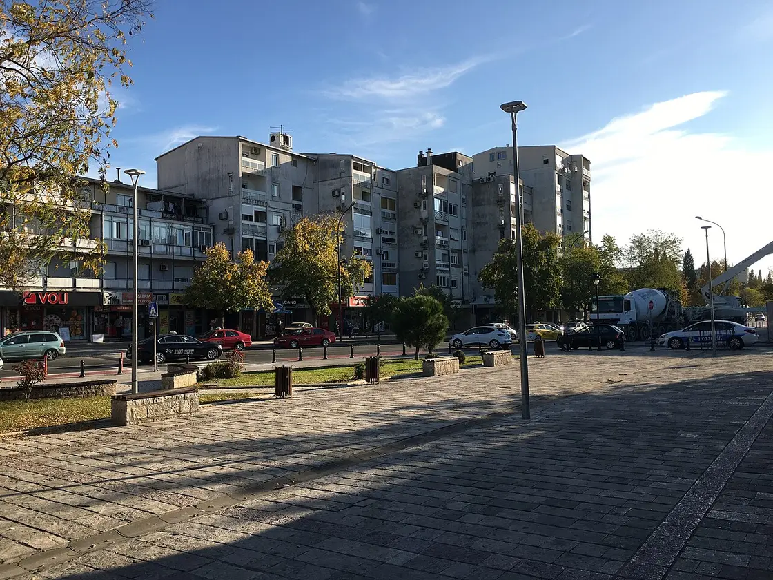 A residential square in Podgorica with mid-century apartment blocks and street-level shops