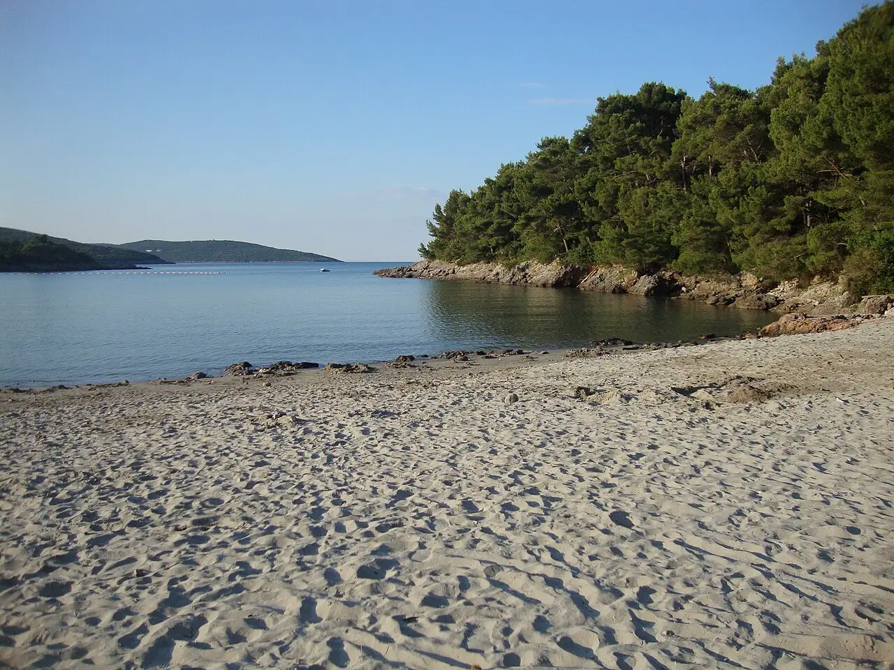 A sandy beach bay on the Lustica peninsula near Tivat with clear shallow water