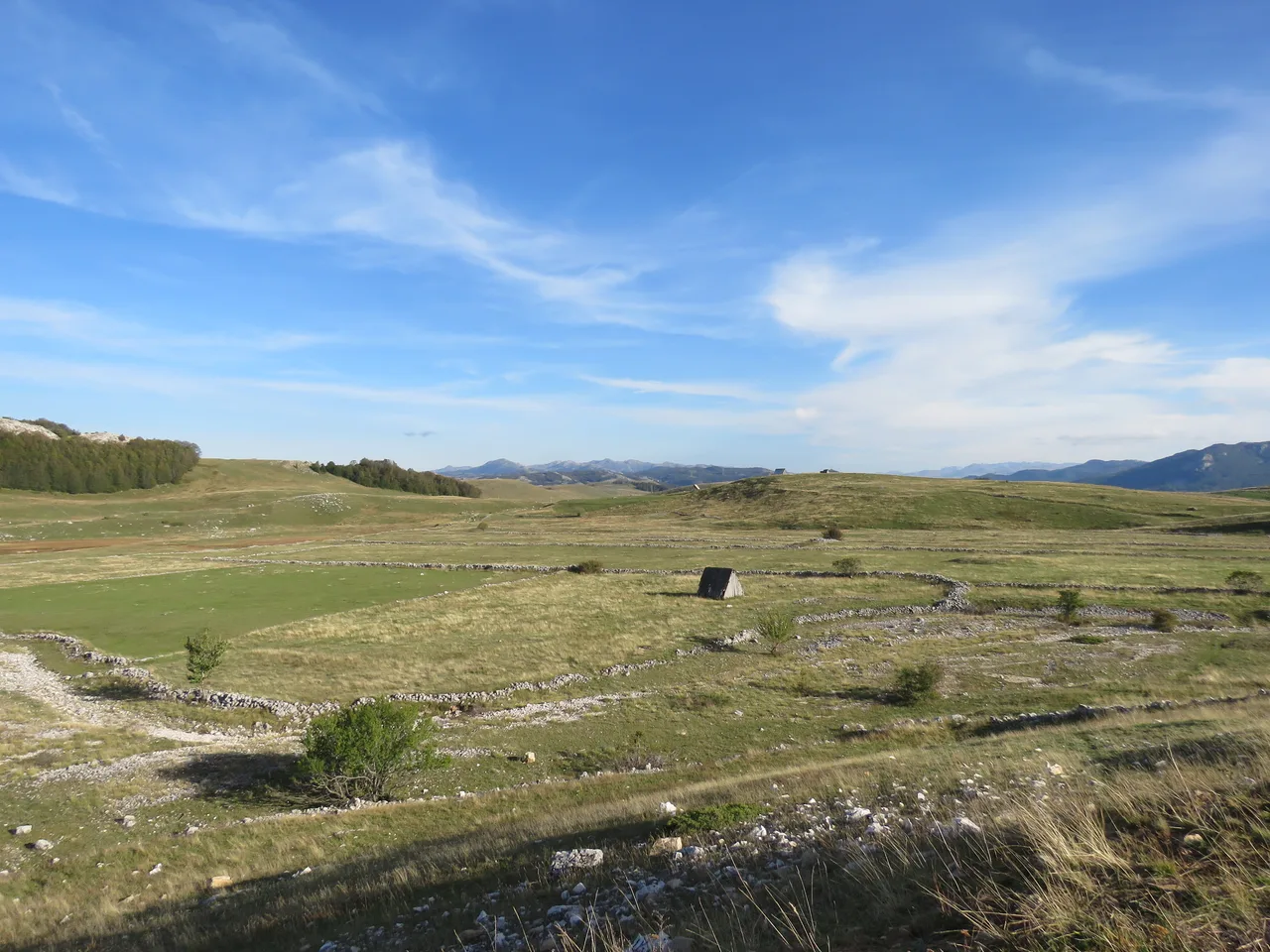 Stone-walled hay fields and scattered cabins on the plateau south of Žabljak in early autumn